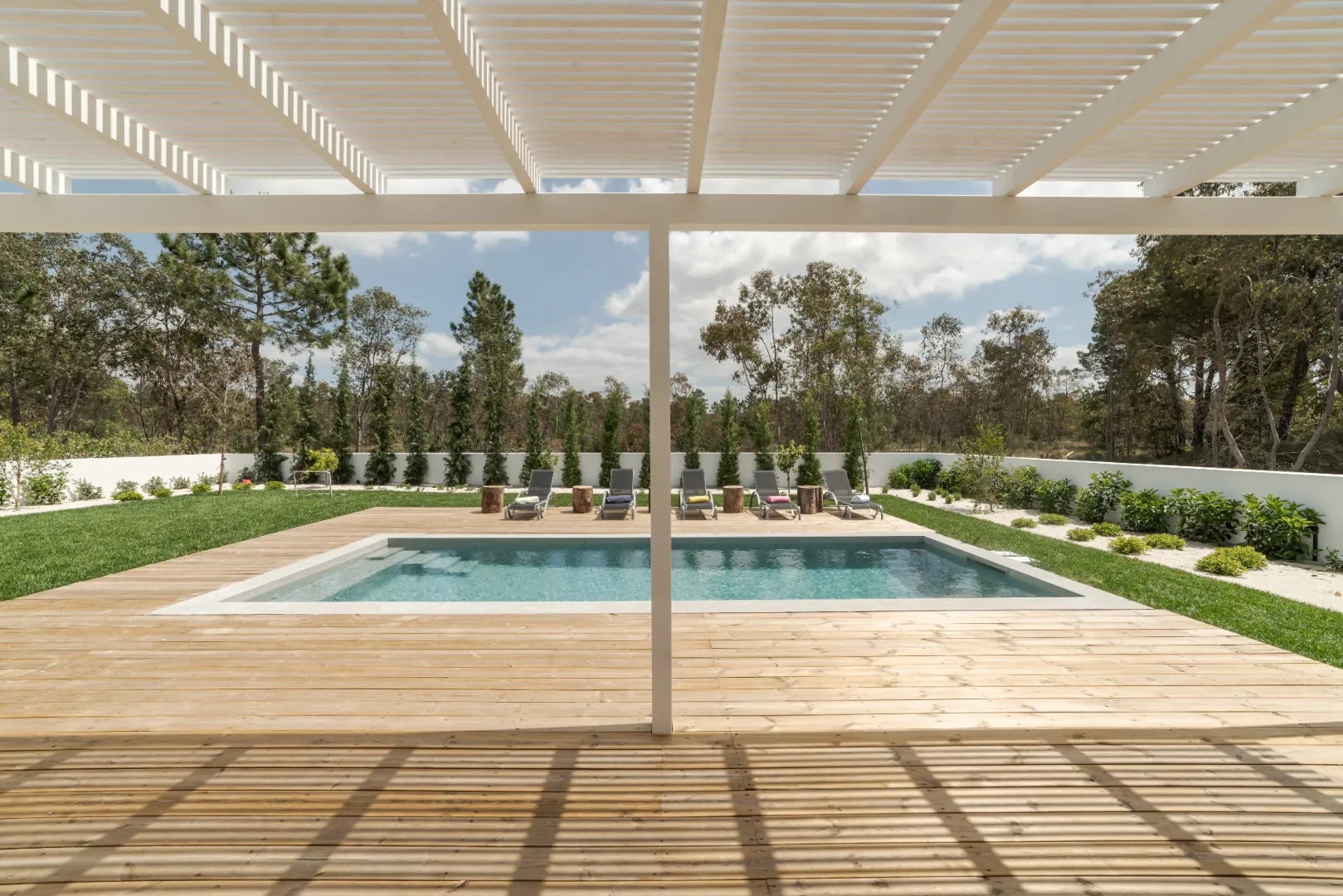 Composite decking around a swimming pool with a shaded pergola